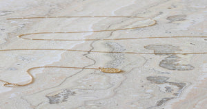 Offat fine gold chain necklace with a small coin pendant on marble