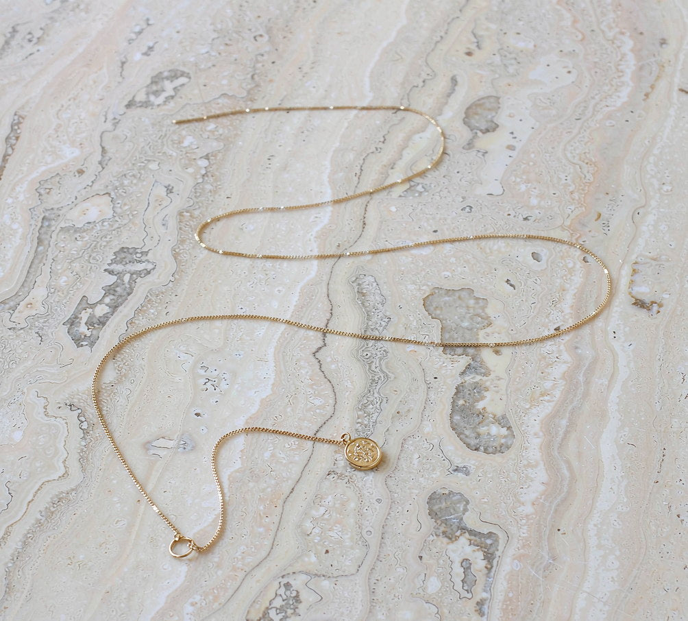 Offat fine gold chain necklace with a small coin pendant on marble